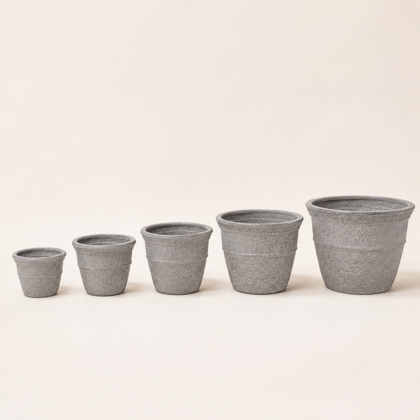 Five grey Cosmos round planters in increasing sizes lined up on a neutral background.