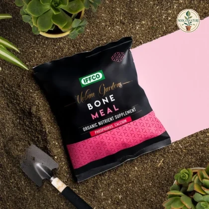 IFFCO Urban Gardens Bone Meal pouch surrounded by soil, a garden trowel, and potted plants.