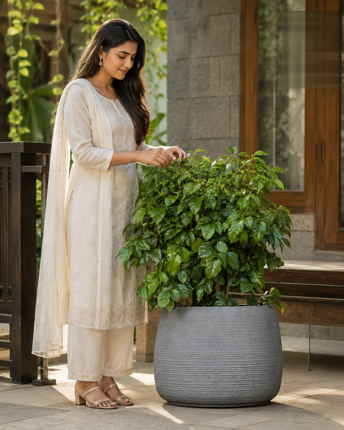Woman in white standing next to a leafy green plant in a blue ceramic Iris Planter.