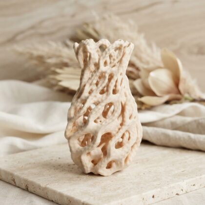 Ivory chain flower vase with an open lattice structure on a stone surface.