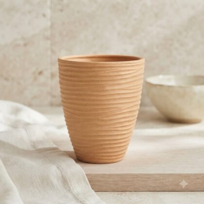 Textured apricot Havana flower vase standing on a wooden surface with a white cloth.